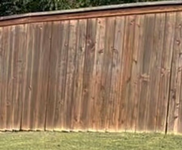A weathered wooden fence with green grass in front.