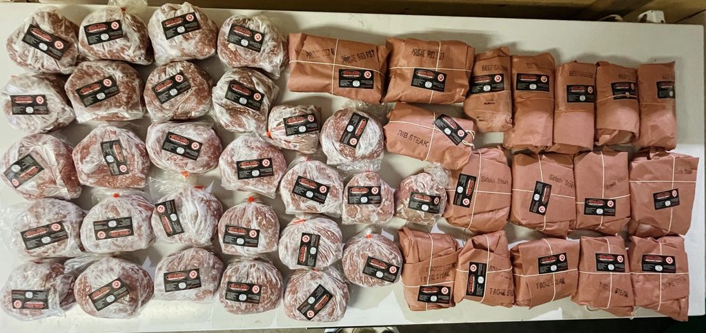 Various cuts of meat wrapped in plastic and butcher paper, neatly arranged on a table.