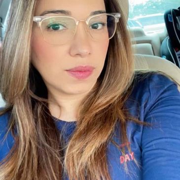 Mujer con gafas y camiseta azul en un automóvil.