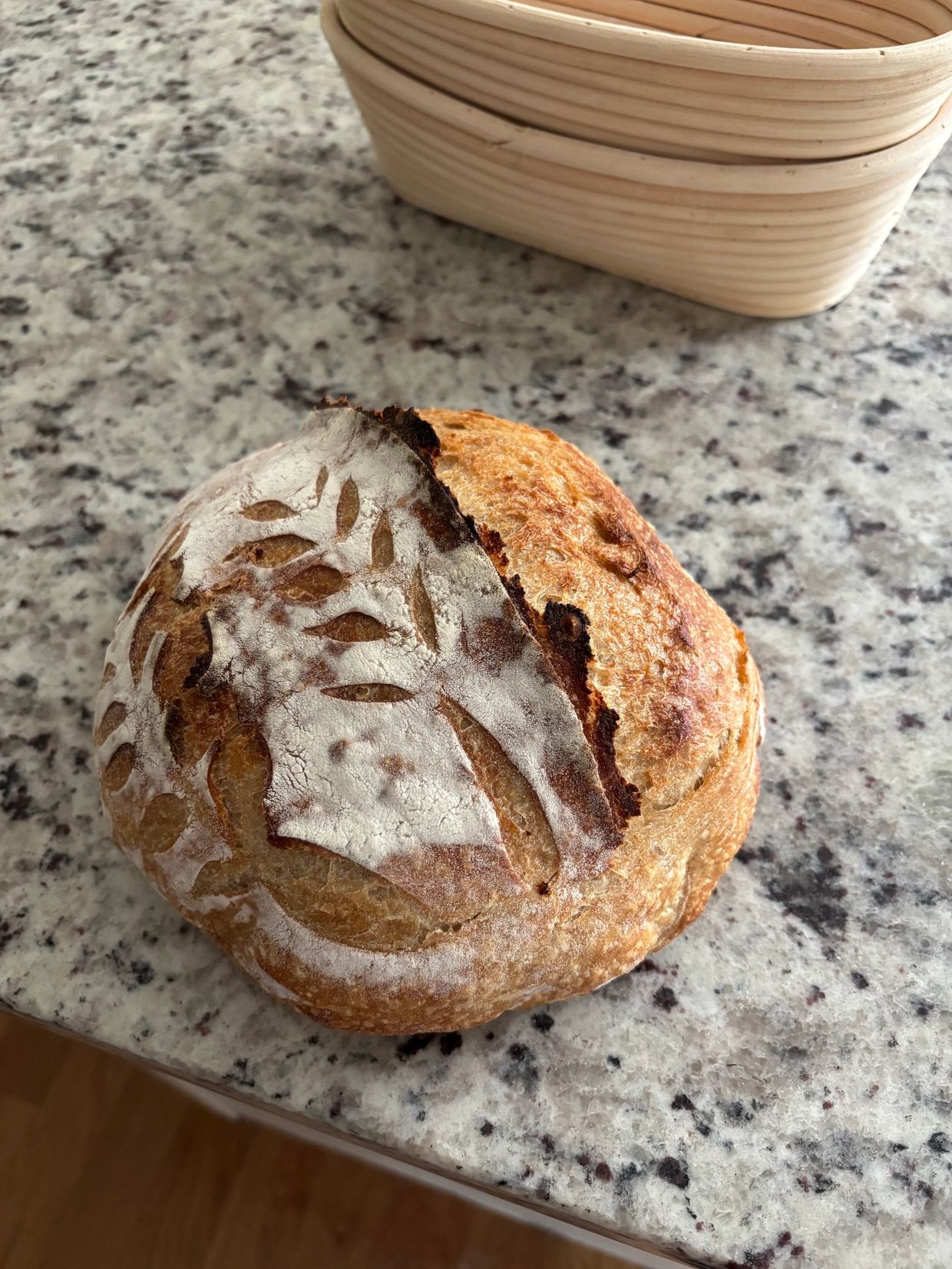 A rustic loaf of sourdough bread with a decorative flour pattern on top.