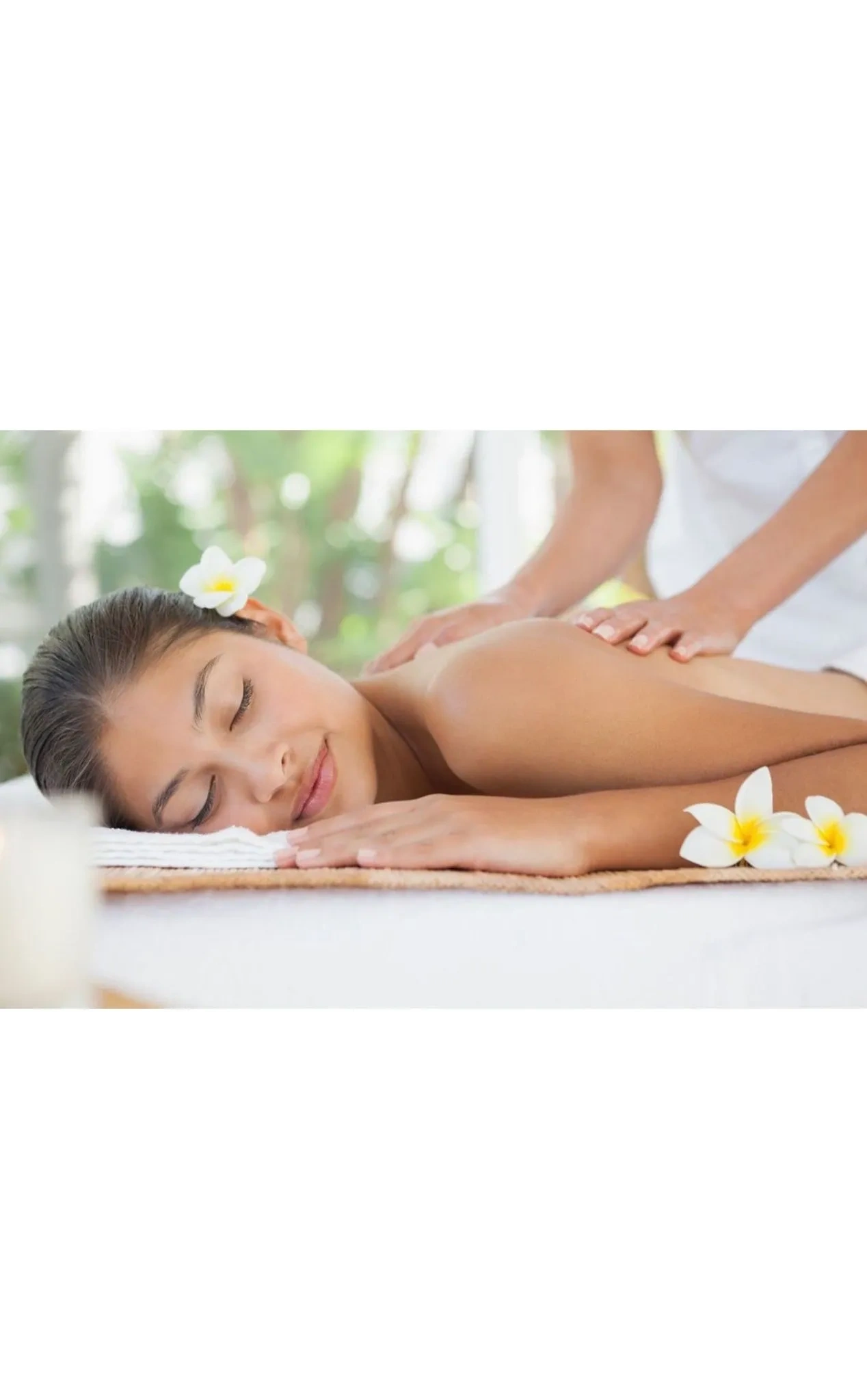 Woman enjoying a relaxing shoulder massage with flowers around.