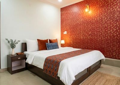 Cozy bed with red accent wall and decorative pillows.