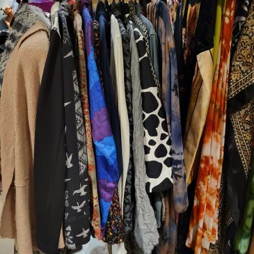 Variety of colorful clothes hanging on a rack.