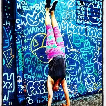 Person doing a handstand against a vibrant graffiti wall. Yoga instructors