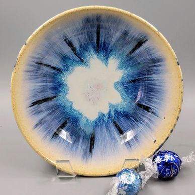 Ceramic plate with blue and black sunburst design and wrapped chocolates.