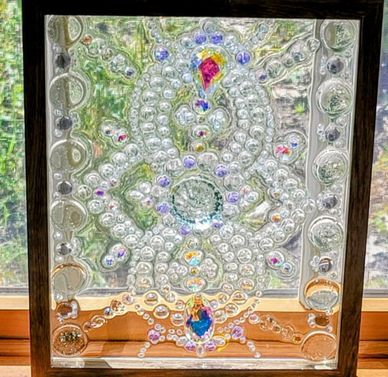 Intricate glass artwork with colorful jewel-like accents in a wooden frame.