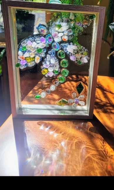 A stained glass artwork of a colorful flower in a wooden frame casting reflections.