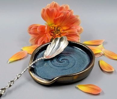 Elegant ceramic dish with a silver spoon and orange flower petals.