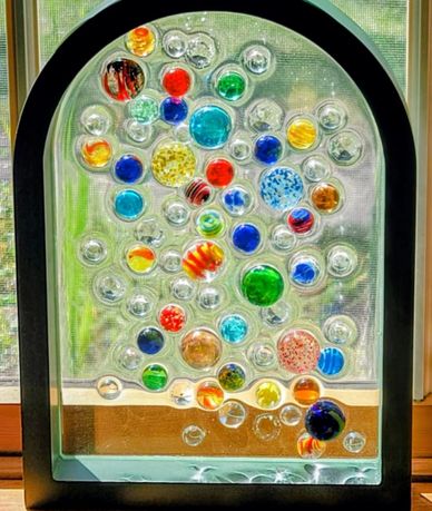 Decorative glass panel with colorful circular designs in a black frame.