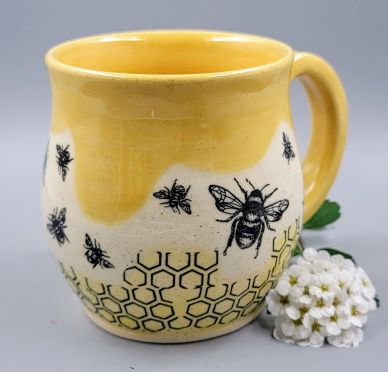 Yellow mug decorated with bees and honeycomb patterns.