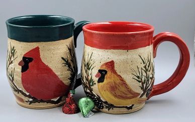 Two ceramic mugs with cardinal bird designs and green and red rims.