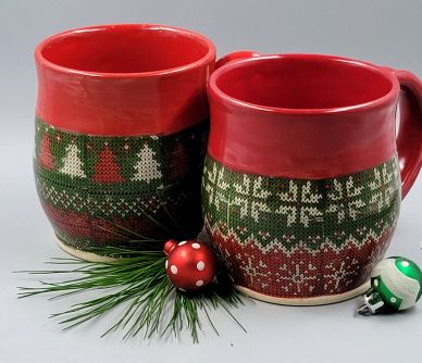 Two red and green mugs with Christmas sweater patterns and ornaments.