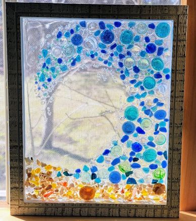 Framed stained glass art with blue, teal, and amber circular pieces forming a wave pattern.