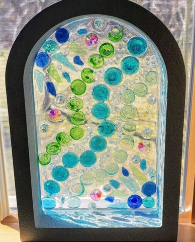 Decorative stained glass panel with colorful circular patterns in a black arch frame.