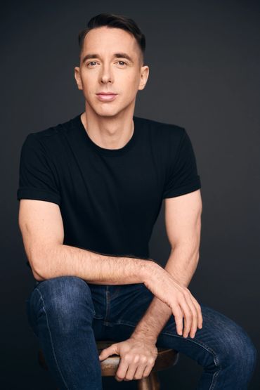 Homme assis avec un t-shirt noir et un jean bleu.