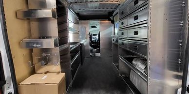 Interior view of a van with organized metal shelving and storage units.