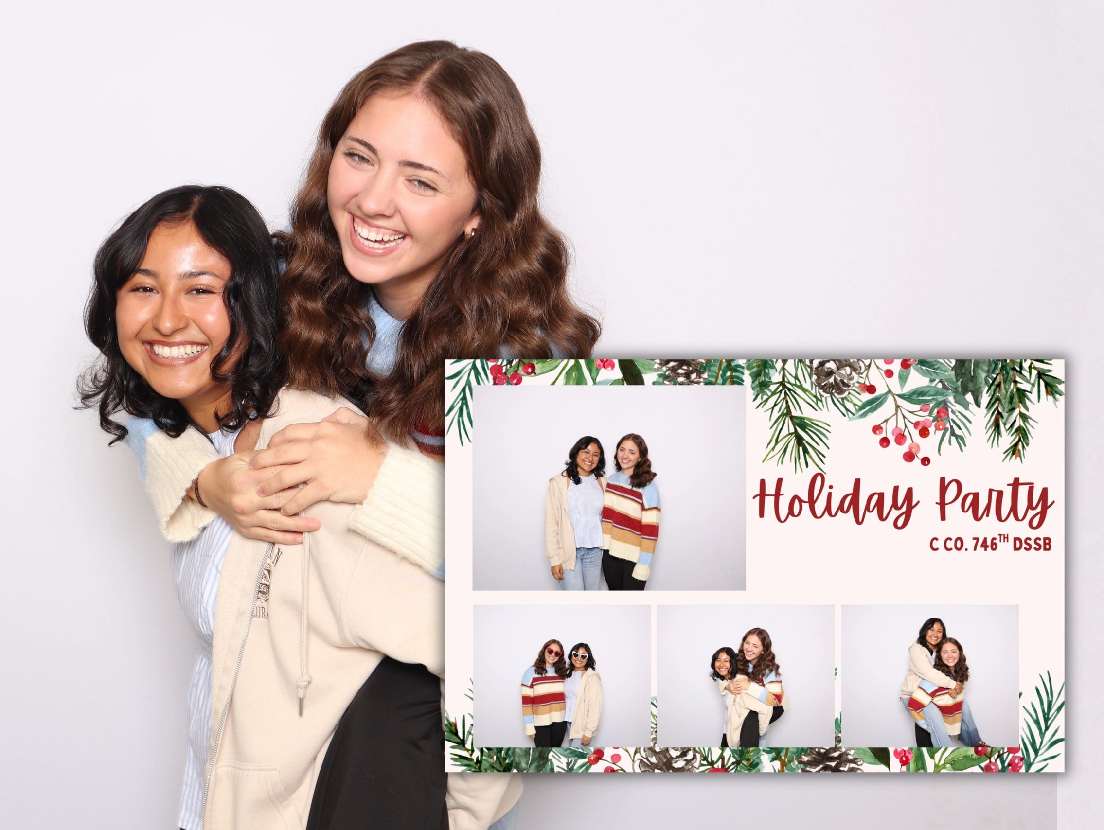 Two friends joyfully hugging at a holiday party photo booth.