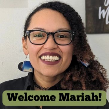 Smiling woman with glasses and curly hair, welcoming Mariah.