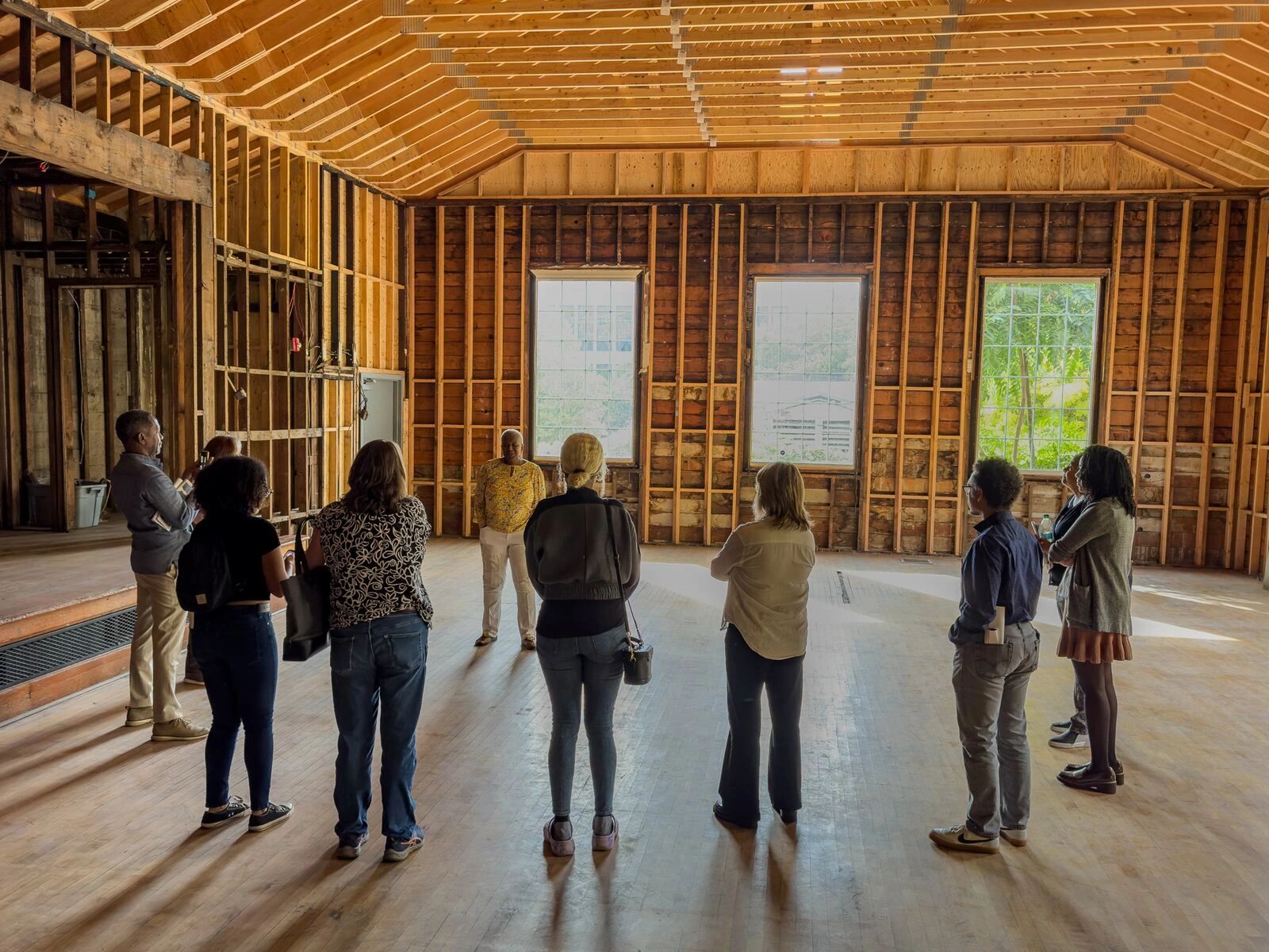 Group of people inside a wooden unfinished room.