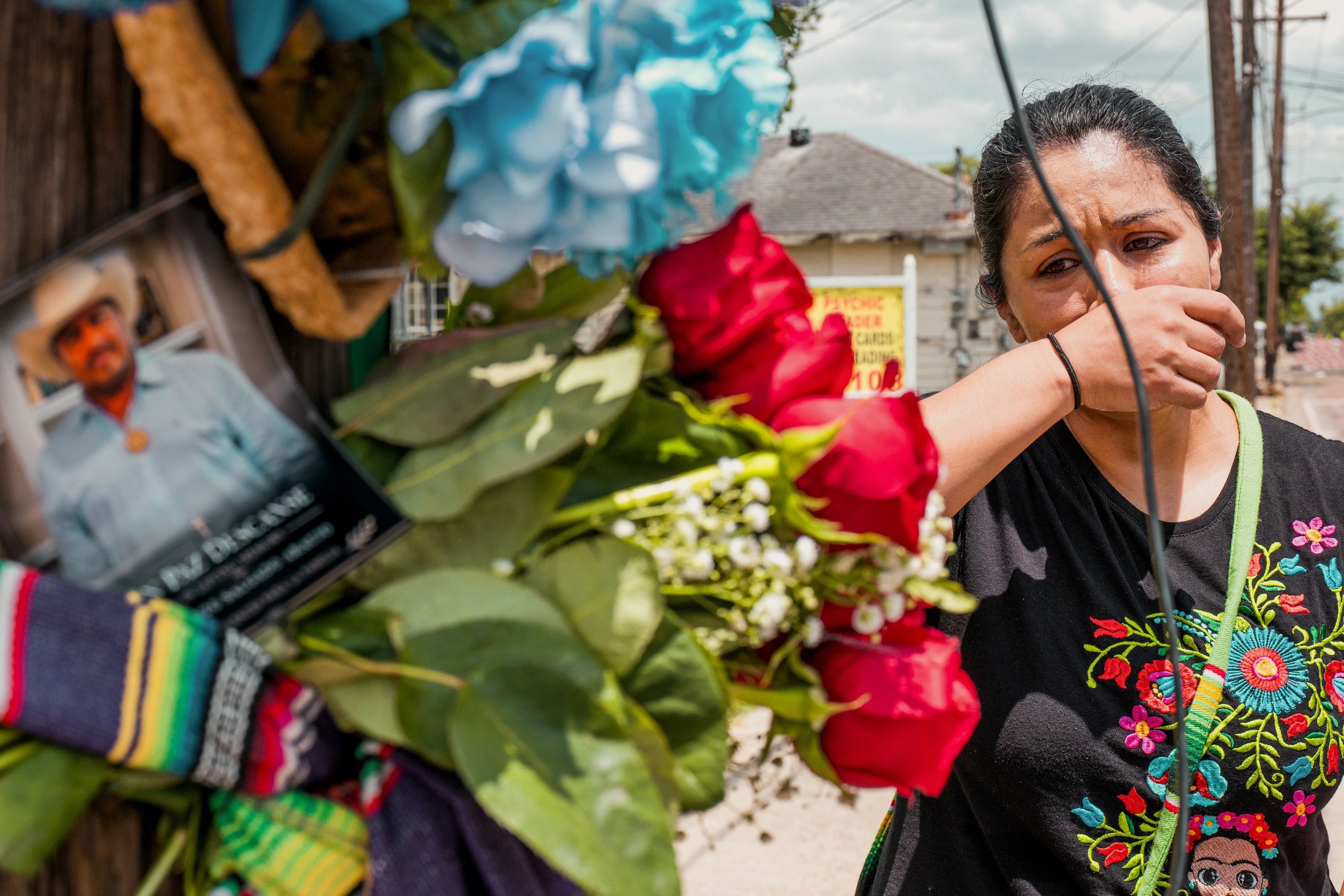 Woman grieving at a memorial with a photo and flowers.