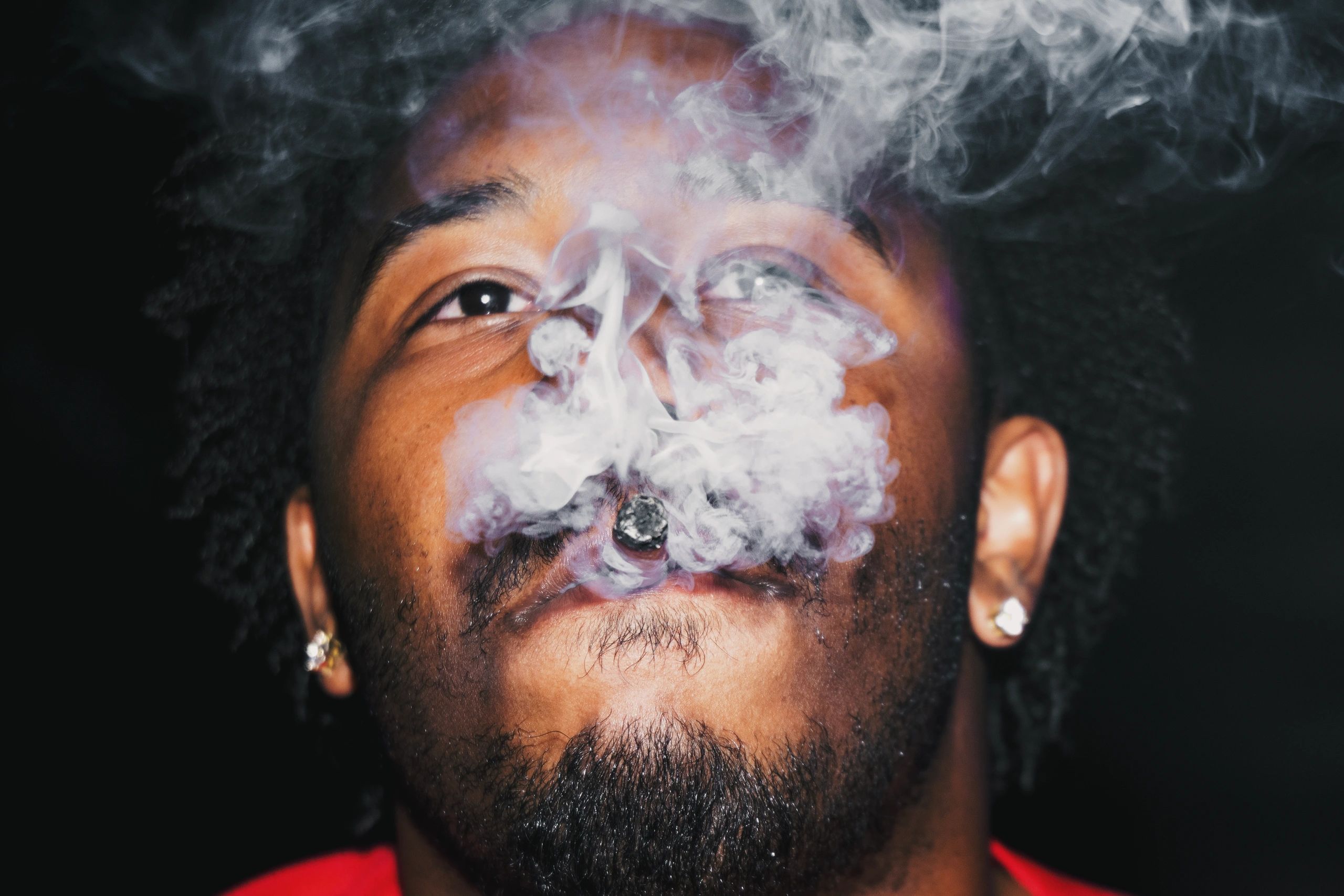 Man exhaling thick smoke from his mouth in a close-up shot.