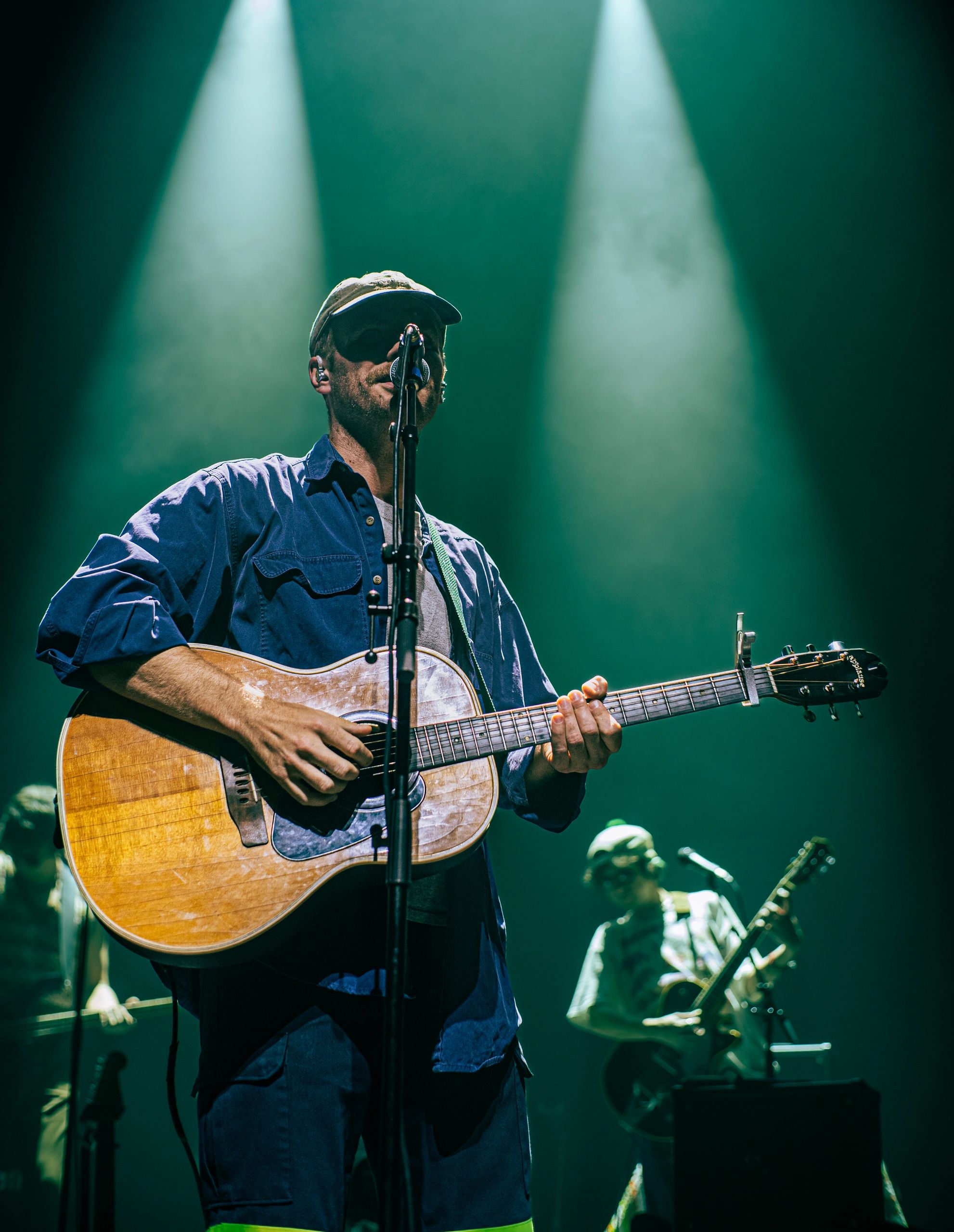 Man playing guitar and singing under stage lights.