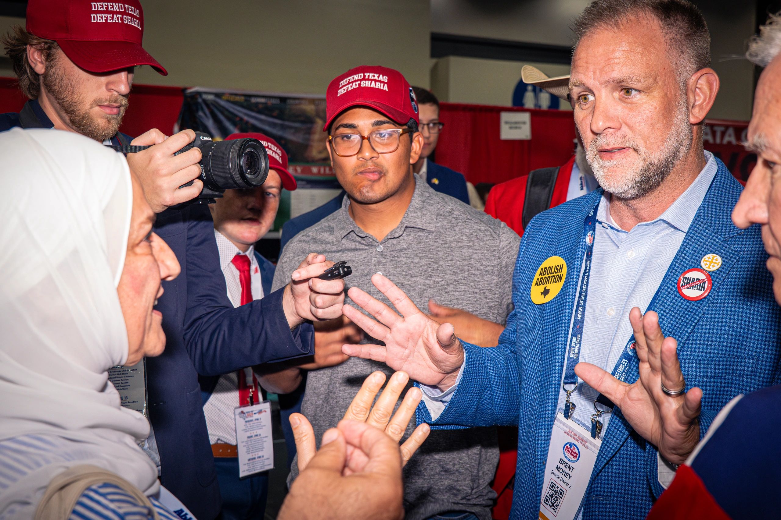 A group discussing with a man wearing anti-abortion and anti-Sharia badges.