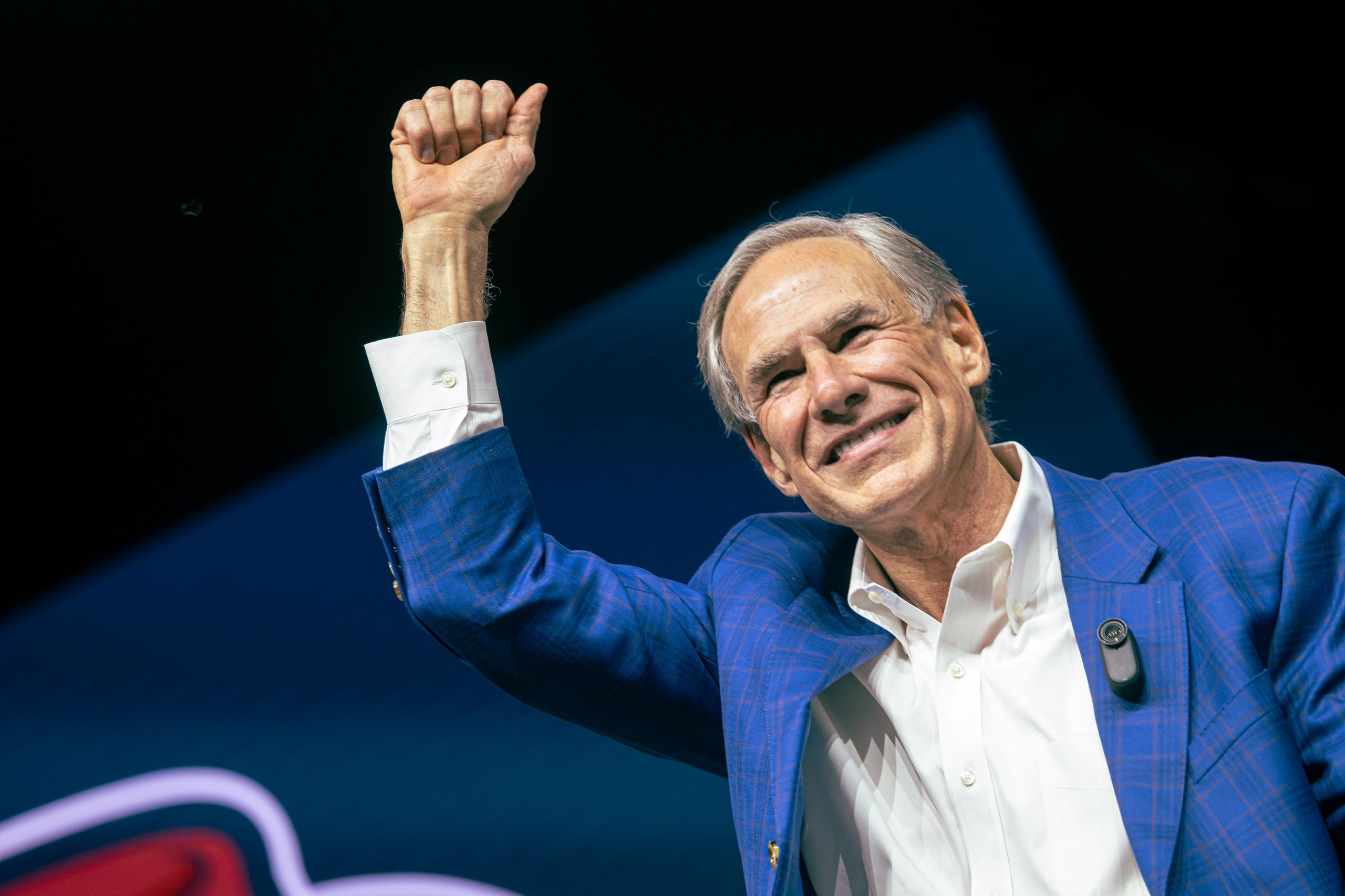 Smiling man in blue suit raising fist in victory.