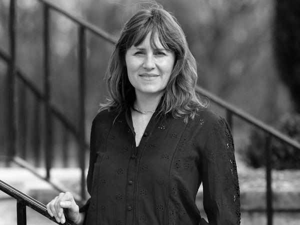 Black and white portrait of a woman standing outdoors by a railing.