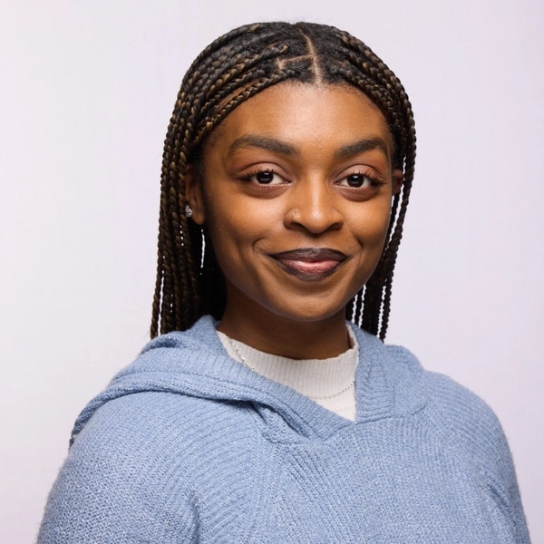 Smiling woman with braided hair wearing a blue sweater.