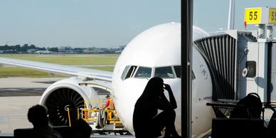 A woman sitting at a boarding gate in front of a plane