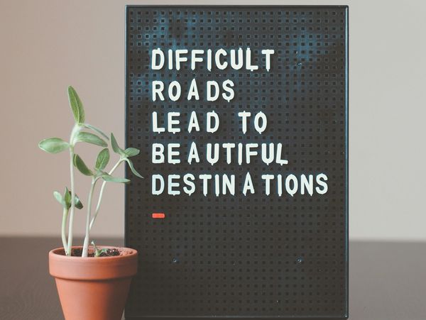 Inspirational quote on a board with a small potted plant.