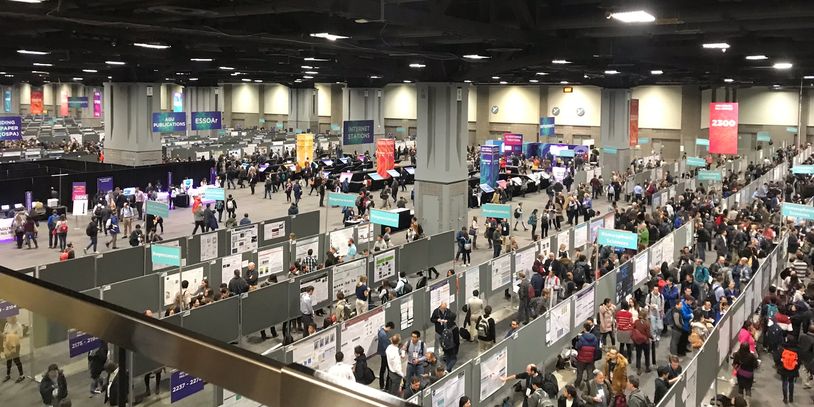Crowded scientific conference with numerous poster presentations and attendees.