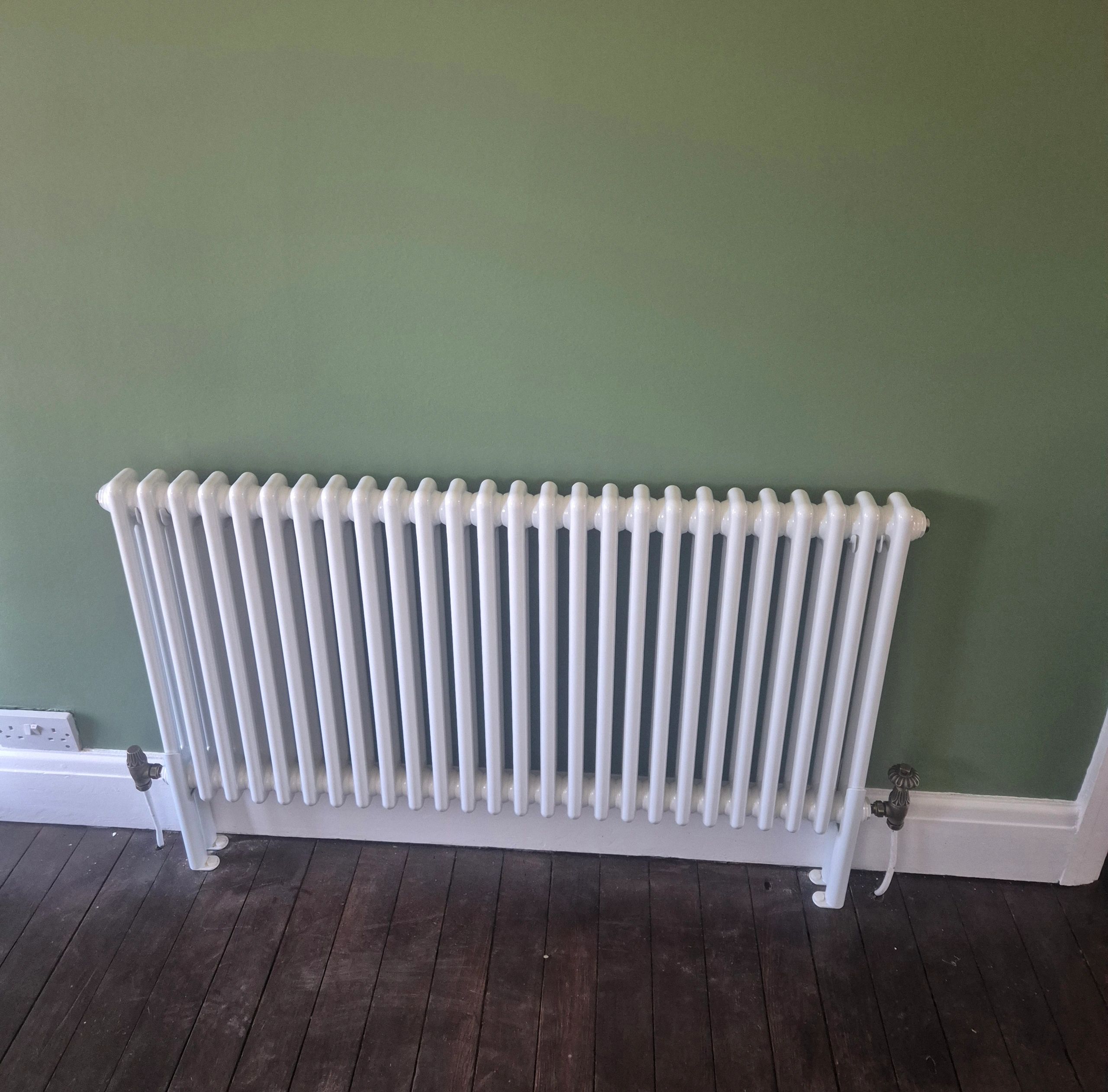 White radiator against a green wall.
