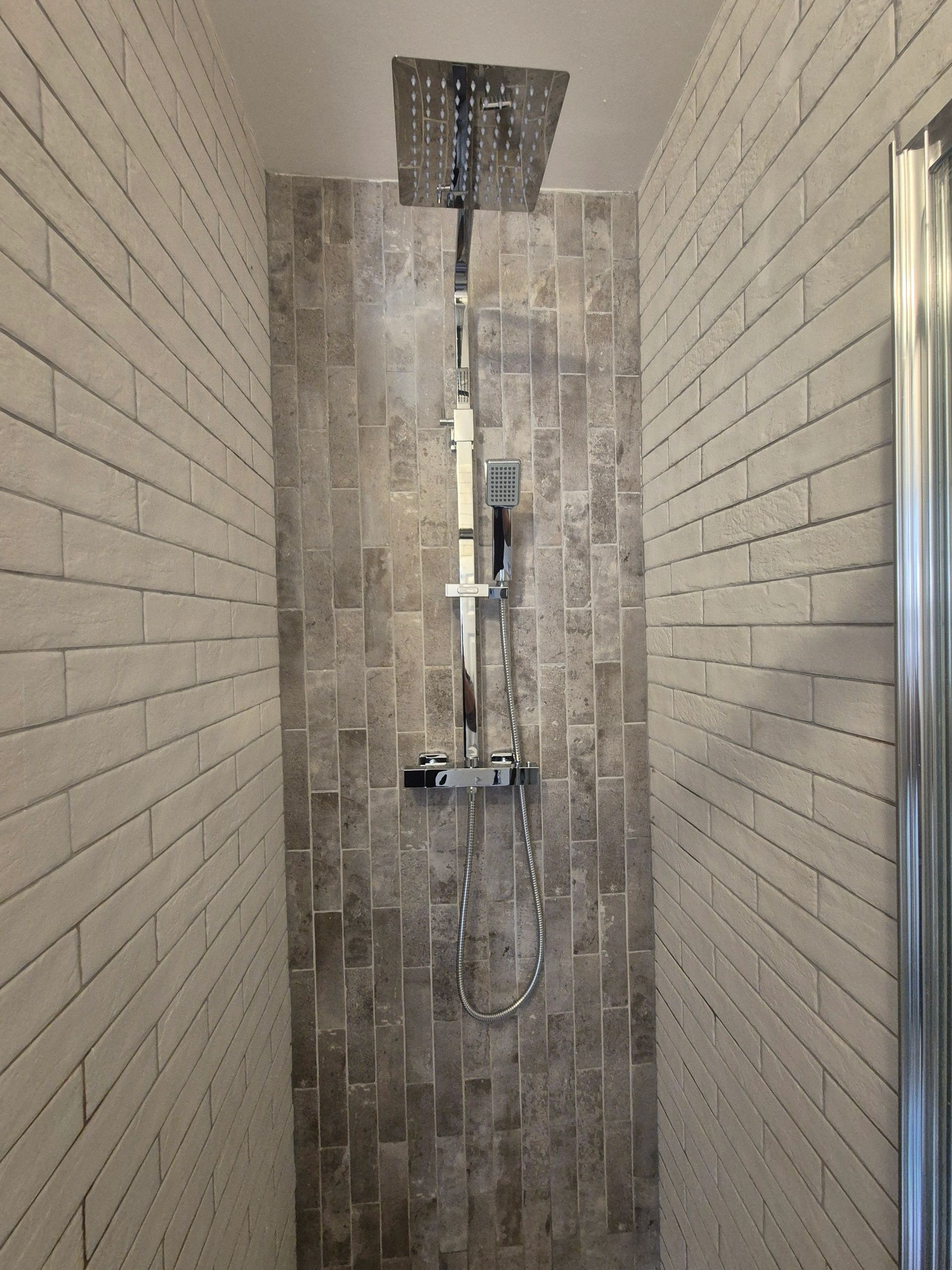 Modern shower with rectangular tiles and two shower heads.