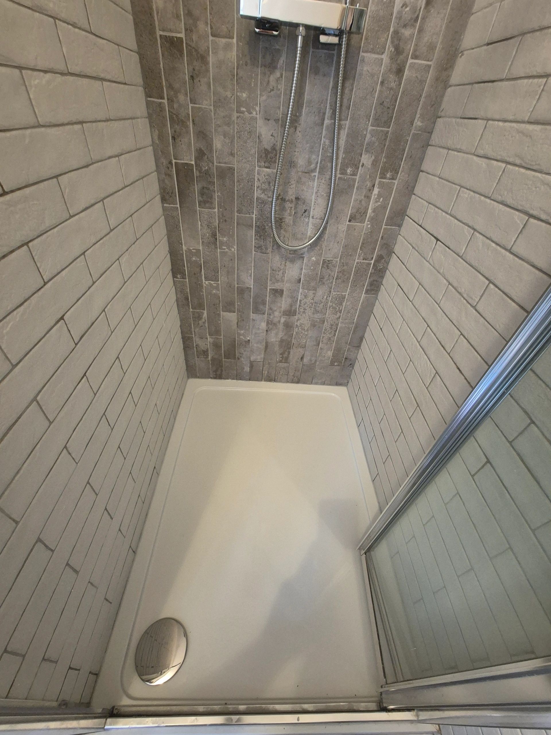 Modern shower stall with tiled walls and glass door.