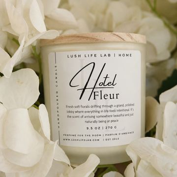 Elegant scented candle labeled 'Hotel Fleur' surrounded by white flowers.