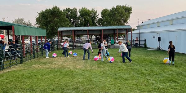 People playing with beach balls on grass near a pavilion.