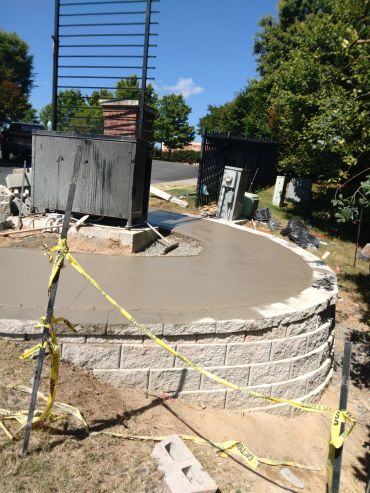 New concrete top on stone retaining wall with caution tape.