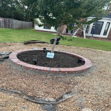 Newly mulched tree bed with a sign in a yard.