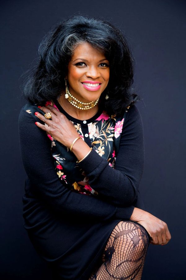 Terees Western, Perfumer & Scent Docent sitting with crossed leg wearing black patterned hosiery.