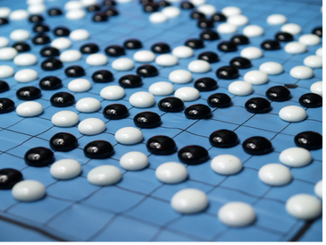 Close-up of a Go board with black and white stones during gameplay.