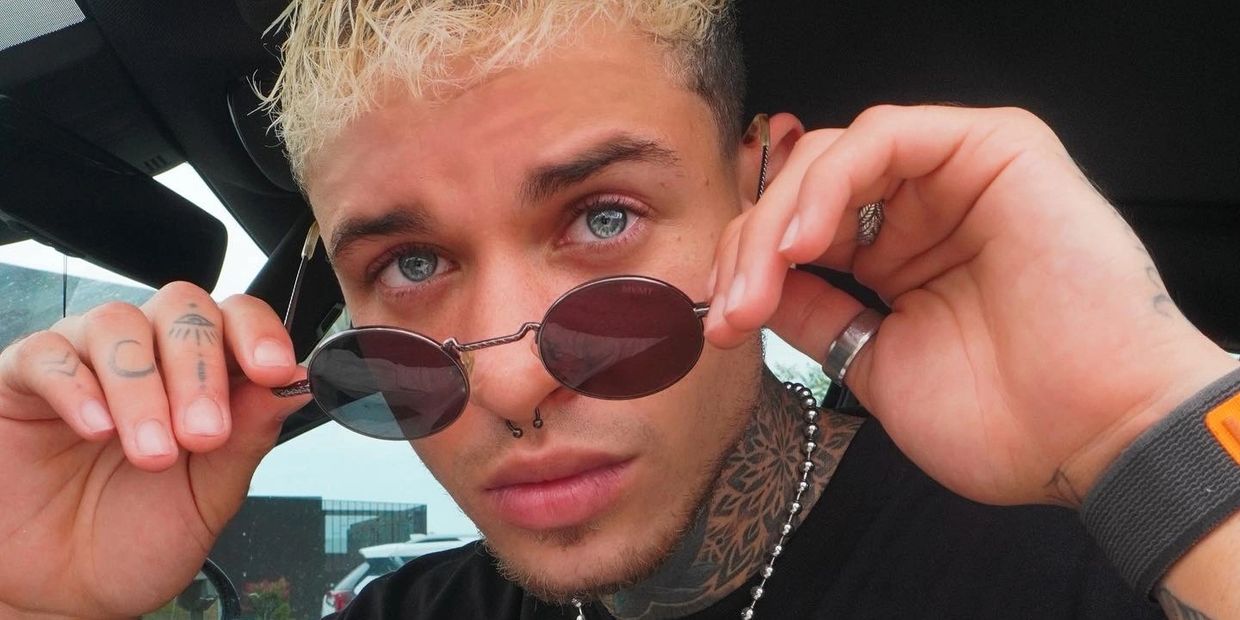 Dominic posing in a car, showcasing a modern, edgy look with tattoos and trendy accessories