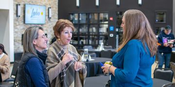 Three women engaged in a lively conversation at a social gathering.
