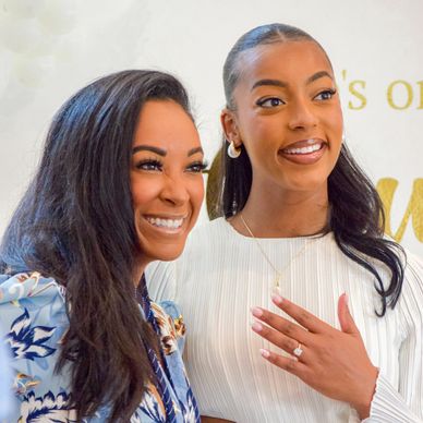 Two smiling women, one showing an engagement ring.