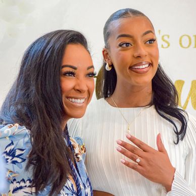 Two smiling women, one showing an engagement ring.