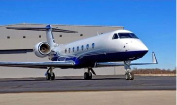 A sleek private jet parked on the tarmac under a clear blue sky.