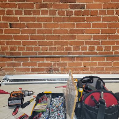 Workbench with tools and screws against a brick wall.