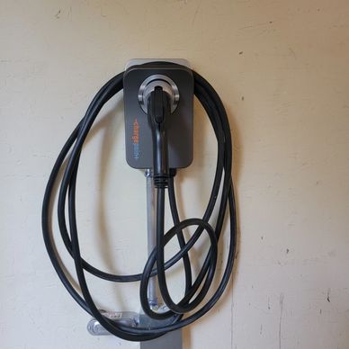 Electric vehicle charging cable coiled on wall mount.