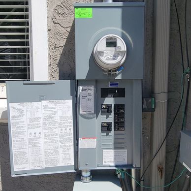 Open electrical panel mounted on an outdoor wall.